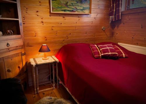 惠拉盖尔济Beautiful Cottage in Hveragerdi的一间卧室配有红色的床和一张桌子上的台灯