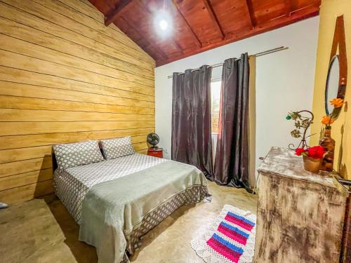 卡兰卡斯Casa Da Cléo Carrancas的一间卧室设有一张床和木墙