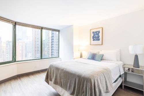 芝加哥ENVITAE 3BR Luxury Corner Loft with Navy Pier Views的白色卧室设有床和大窗户