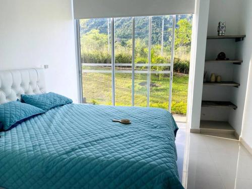 伊瓦格Hermosa casa campestre!的一张带蓝色棉被的床和大窗户