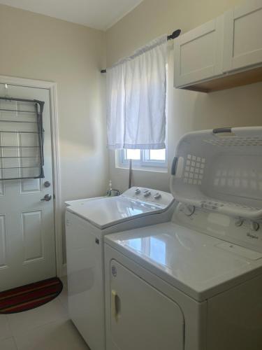 卢西Seamist villa @Oceanpointe Lucea comfy 2BR w/pool gym & parking的白色的厨房配有水槽和洗碗机