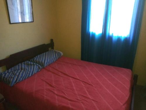 埃尔莫拉尔La Griselda的一张带红色棉被的床和一扇窗户