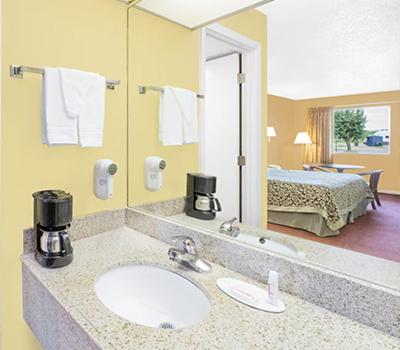 北小石城Travel Inn North Little Rock的一间带水槽和镜子的浴室以及一张床