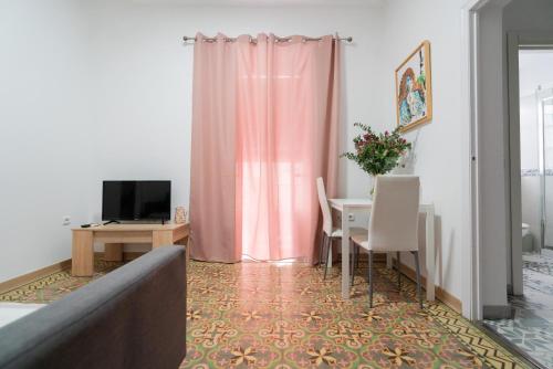 阿亚蒙特Apartamento La Inmaculada的客厅配有桌子和粉红色窗帘