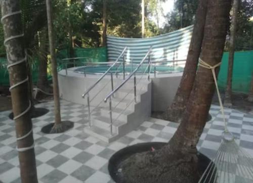 阿利鲍格Bhumi Holiday Home的一座带楼梯的游泳池,在瓷砖地板上有一棵树