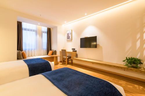 郑州素朴酒店(郑州CBD国际会展中心店)的酒店客房设有两张床和一台平面电视。
