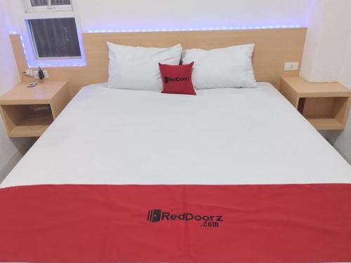 KedatonRedDoorz Syariah @ Gedong Air Lampung的一张白色的床,上面有红色的沙发