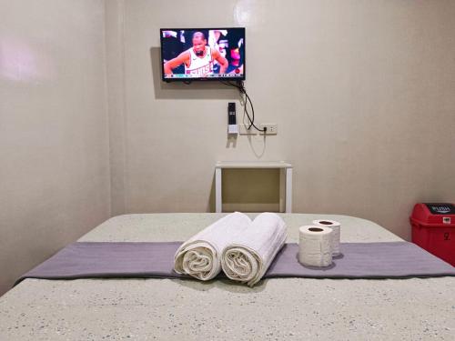 卢纳将军城#1 Green Room Inn Siargao的一间卧室配有带毛巾的床和电视。