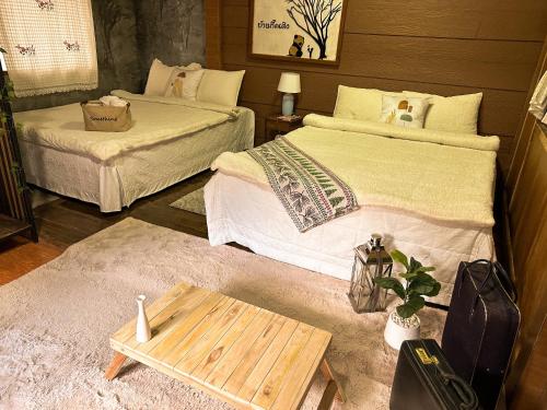 湄安บ้านพักกึ๊ดเติง แม่กำปอง เชียงใหม่的一间设有两张床和一张桌子的房间
