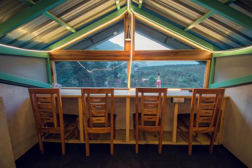 马拉里The Forest Pinnacle & Café, Manali的配有大窗户的客房内的桌椅