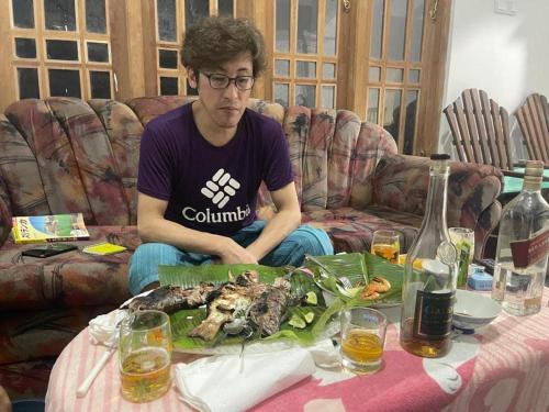 瓦斯卡杜瓦Shenumi villa的坐在沙发上,坐在桌子上,吃一盘食物的人