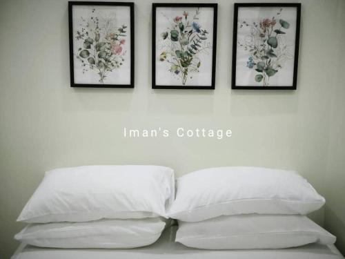 居林Iman’s Cottage Hospital Kulim Hitech的四幅画在床上方墙上,上面有四个枕头