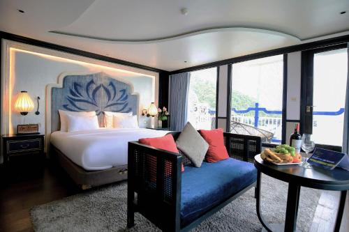 下龙湾Lotus D'Orient Cruise的一间卧室配有一张床、一张沙发和一张桌子