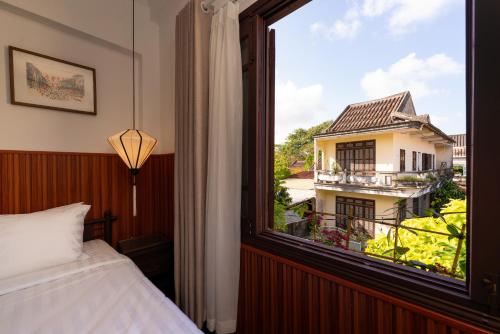 会安Hoianese Heritage Hotel - Truly Hoi An的一间卧室设有窗户,享有建筑的景色