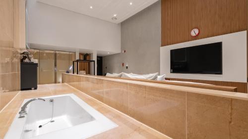天安市Hotel Schweizer Dorf Cheonan的带浴缸的大型浴室和电视。