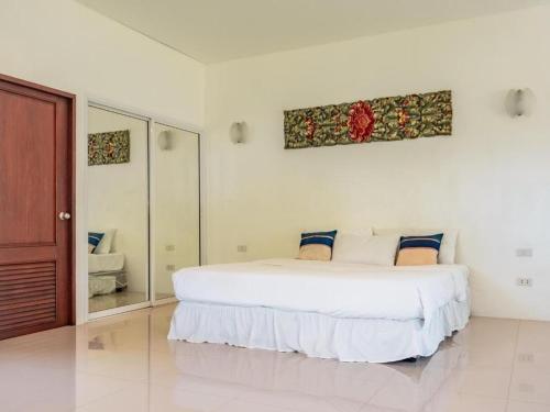 塔林甘海滩Am Samui Resort Taling Ngam的白色卧室设有一张大床和镜子