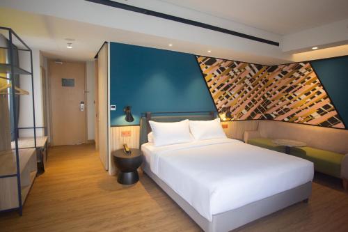 当格浪ibis Styles Serpong BSD City的卧室配有白色的床和带葡萄酒瓶的墙壁