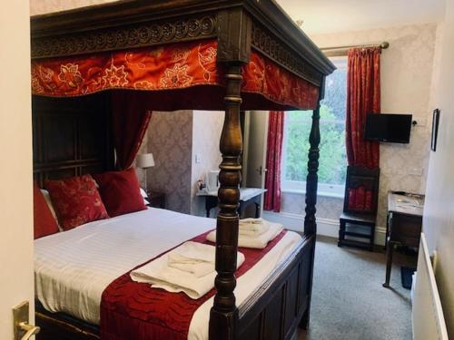 卡斯尔顿Ye Olde Nags Head的一间卧室配有一张带红白色床单的天蓬床。