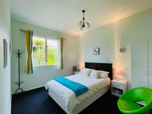 皇后镇Kelvin Garden Villa的一间卧室配有一张床和一把绿色椅子
