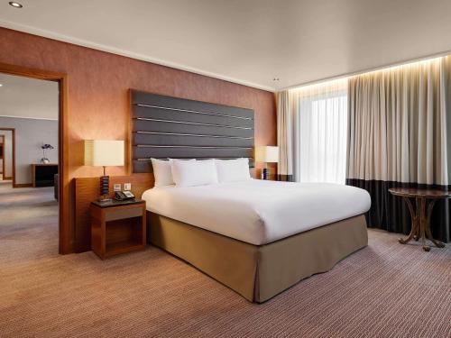 希灵登索菲特伦敦希斯罗酒店的一间大卧室,配有一张大床和一张书桌
