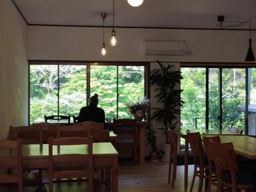 Inoそらやまゲストハウス Sorayama guesthouse的坐在餐厅桌子旁,望着窗外的人