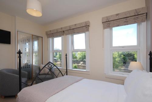 约克Abbey Guest House York的一间卧室设有2扇窗户和1张床及椅子