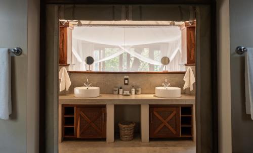LentswelemoritiTuli Safari Lodge Mashatu的一间带两个盥洗盆和窗户的浴室