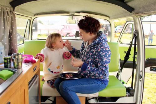 Great OuseburneDub Indie - The 100% Electric Classic Camper的坐在货车里的女人和一个小女孩