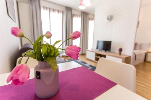 布达佩斯Colours Apartments Deluxe with FREE Parking的花瓶,花朵粉红色,坐在桌子上