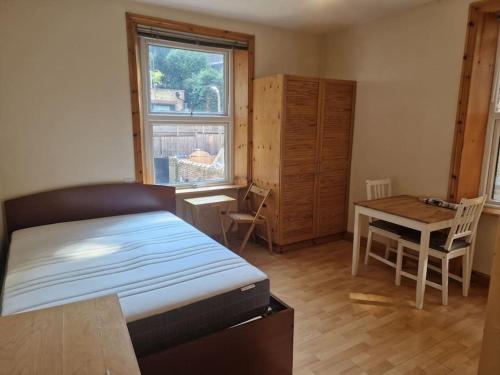 伦敦Bright studio apartment Highgate的一间卧室配有一张床、一张桌子和一张桌子