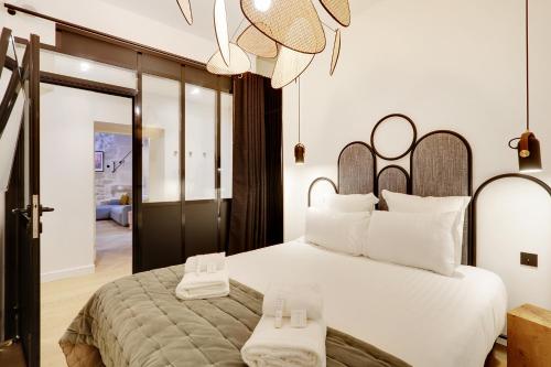 巴黎Pick A Flat's Apartments in Place des Vosges - Rue de Birague的卧室配有一张白色大床和吊灯。