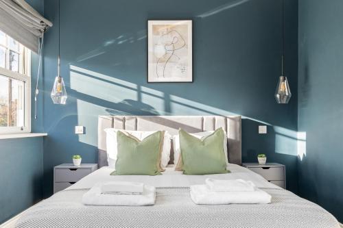 伦敦The Putney Villa的一间卧室拥有蓝色的墙壁,配有一张带两个枕头的床