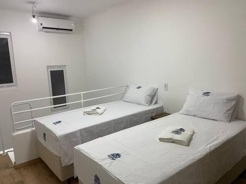 约恩维利Loft no Espinheiros - Joinville/SC的白色墙壁客房的两张床