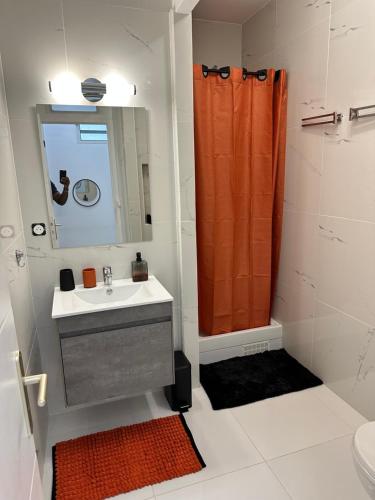 皮特尔角城Cyrus appartements的浴室设有水槽和橙色淋浴帘