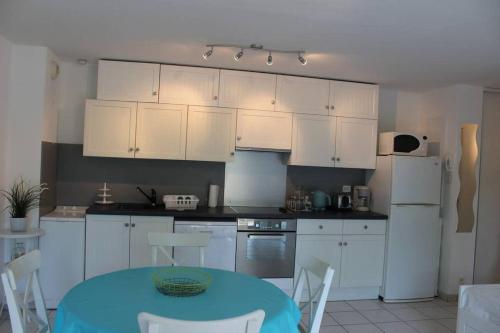 阿雷斯appartement cosy et nature au coeur du Bassin的厨房配有白色橱柜和蓝色的桌椅
