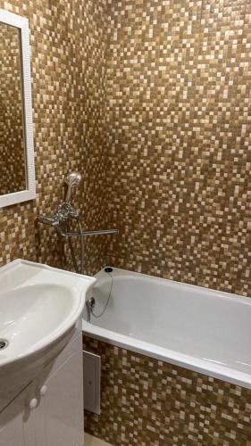 乌斯季卡缅诺戈尔斯克Однокомнатные апартаменты的浴室配有盥洗盆和浴缸。