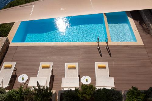 塞沃塔VILLAS MIRO - Luxury Villas with Direct Sea Access for 14 people的享有带白色椅子的游泳池的顶部景致
