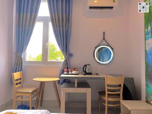 永隆Hotel Phước Thịnh的配有桌椅和镜子的客房