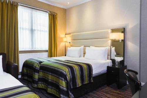 伦敦Park Grand Hyde Park的酒店客房设有两张床和窗户。