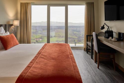 瓜尔达Hotel Versatile的配有一张床、一张书桌和一扇窗户的酒店客房