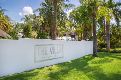 贝拉贝拉The Villa Manor & Spa的棕榈树白色墙壁上的标志