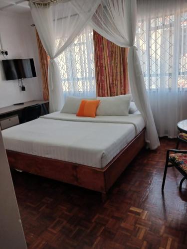 基苏木Annodas Homes Milimani Kisumu的一间卧室配有一张带橙色枕头的床