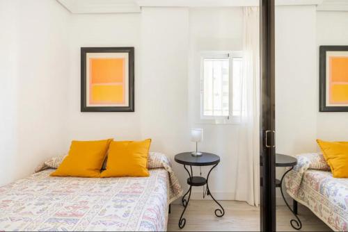 塞维利亚Apartamento amplio con 4 habitaciones y 2 baños - Great apartment with 4 rooms - 2 baths的一间卧室配有两张带黄色枕头和桌子的床。