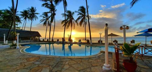 班布里Sai Rock Beach Hotel & Spa的棕榈树泳池和日落背景