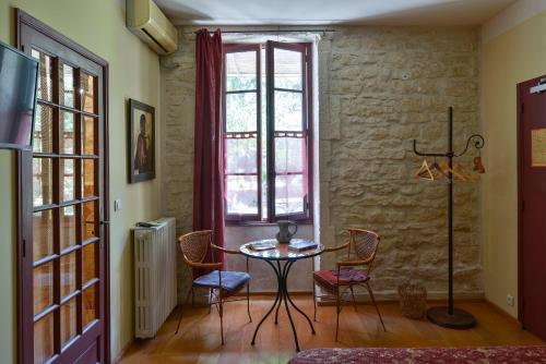 Saint-Étienne-du-GrèsHôtel Mas Vidau Porte des Alpilles的客房设有桌椅和窗户。