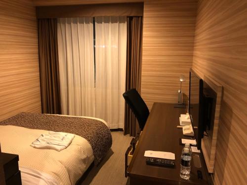 福岛JR-East Hotel Mets Fukushima的酒店客房配有一张床和一张带电脑的书桌