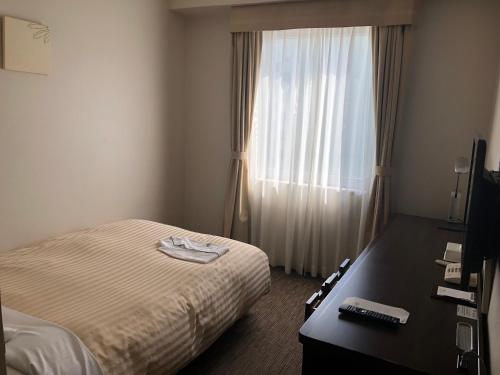 福岛JR-East Hotel Mets Fukushima的配有一张床、一张书桌和一扇窗户的酒店客房