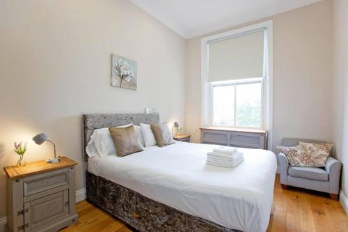 伦敦Stunning 1bed Kensington的卧室配有一张白色大床和一把椅子