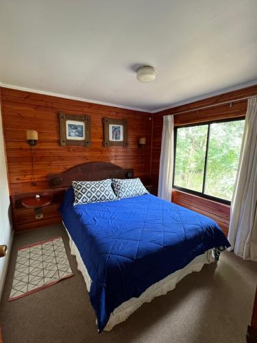 迪卡托Cabaña Pingüeral (Derecho a piscina verano)的一间卧室配有一张带蓝色棉被的床和窗户。