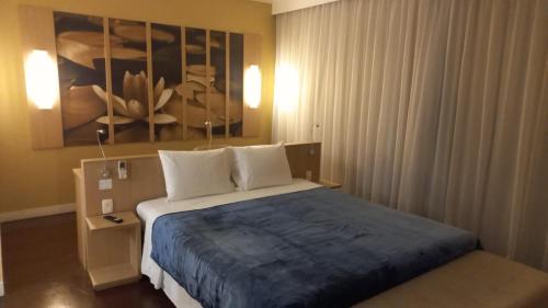 马瑙斯###SENSACIONAL### MERCURE APART HOTEL PREMIUM的卧室配有一张床,墙上挂有绘画作品